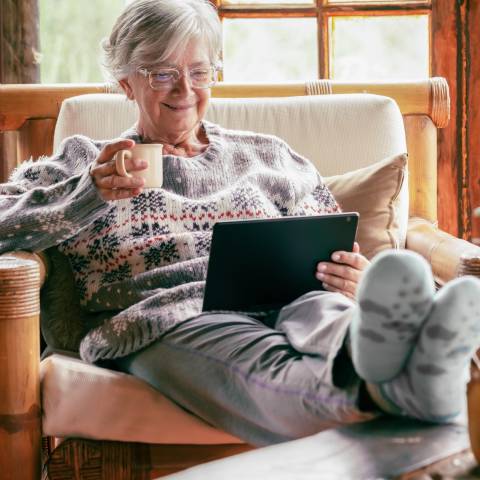 Une femme âgée boit une tisane et porte des vêtements chads pour lutter contre le froid en hiver