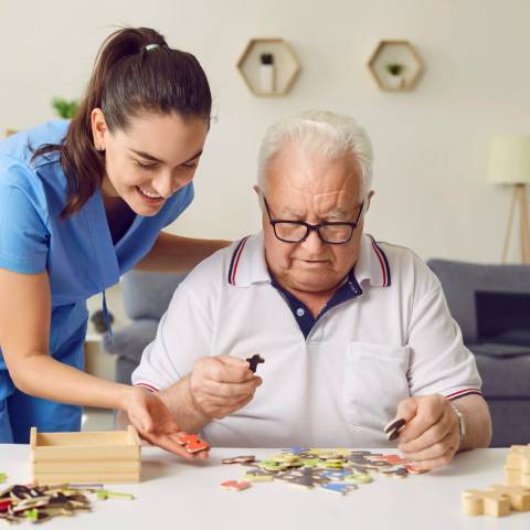 Une animatrice aide un résident atteint d'Alzheimer en UHR à faire un puzzle.