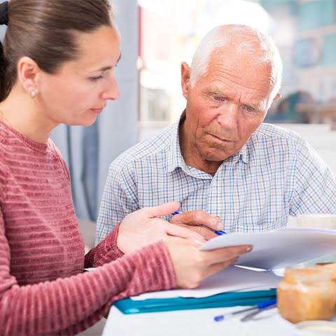 Montant de l'ASPA en 2026 Une jeune femme explique à son père âgé les nouveaux montants de l'ASPA en 2026